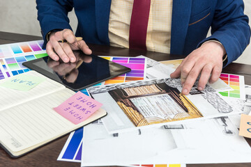  designer is working on the choice of color and repair of a modern apartment. Sketch flat and colored patterns on desk in office.