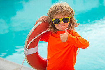 Little lifeguard show thumb up, ok. Summer kids holidays. Happy child playing with lifebuoy in the...