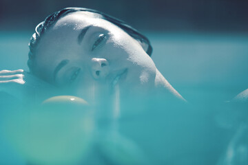 Fototapeta premium Beautiful Girl’s Face Portrait. Woman Floating In Pool At SPA And Looking At Camera.