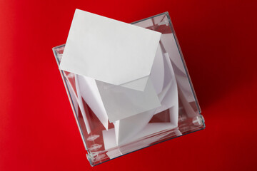 Voting box with bulletins on red background, top view