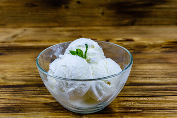 Glass bowl with ice cream balls and mint leaf on a wooden table