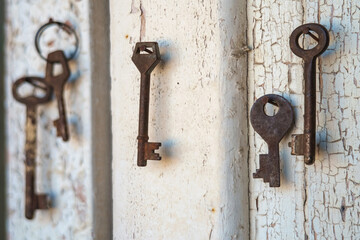 Old rusty keys on the shabby wooden door frame with broken white paint
