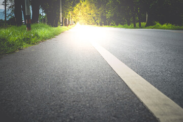 Empty asphalt road through the green field and tree on the forest in summer day. Highway in rural scenes use land transport and traveling background. Trip and journey perspective concept.