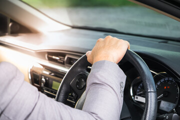 Businessman driving the luxury car on his morning commute to work. The handsome man's hand touched the steering wheel of his automobile with confidence in his road trip.