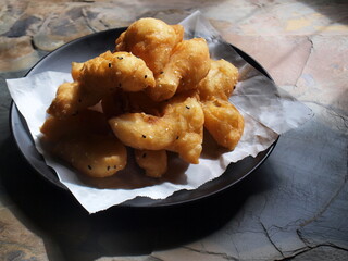Chinese donut or chinese bread on a black plate. deep-fried doughstick in blotting paper and natural light by window pasted on stone floor with copy area. Selective focus