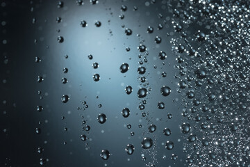 Water drops and water mist hang picturesquely on a glass shelf with studio lighting in blue and black.