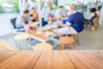 Wood table in front of group young friends come to meet and laughing enjoy in the cafe blur background. Brown wooden desk in front of crowd group talking in coffee shop. Empty counter in restaurant.