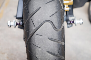 Rear view of motorcycle tire on the road with copy space. Close up classic motorbike tyre tread wheel on the asphalt roadway.  © Chaiyaphruek