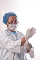 Protecting healthcare workers from infection. A female doctor puts on medical gloves on a white isolated background and smiles. Personal protective equipment before examination of patients