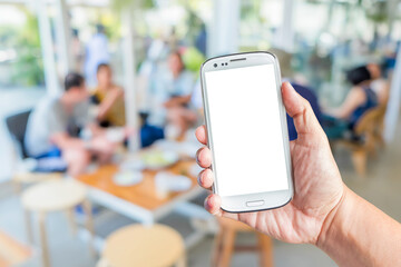 Hand holding a white smartphone with mockup blank screen in the cafe. Touch screen mobile phone with a blurred background of group young friends enjoy a meal in the coffee shop.