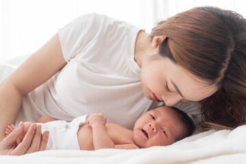 woman and new born boy relax. mother breast feeding baby. family at home. happy mother and baby. young mother holding her newborn child. mom nursing baby. mother and baby child on a white bed.