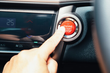 Finger about to touching and press button function start and stop luxury car engine in the automobile on the road trip. Owner and dealership concept