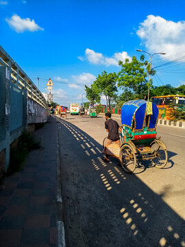 A rickshaw puller doing hard job under hot summer sun shine.