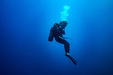 Scuba diver woman standing still in deep blue
