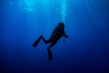 Scuba diver  standing in the deep blue with rays of light