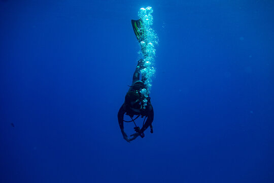 Scuba diver entering water in a vertical position making bubbles
