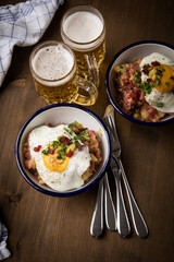 Norddeutscher Hamburger Labskaus mit Rindfleisch Corned Beef, Rote Beete, Kartoffeln, Saure Gurken, Spiegelei, Rollmops und Bier auf Holztisch