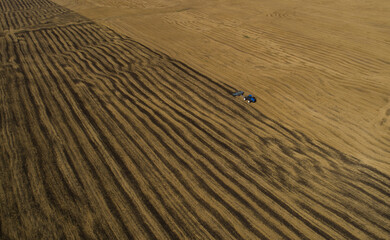 The tractor plows the field for sowing wheat. A beautiful new tractor in the field leaves a strip of beautiful background behind it. Agroindustry. Aerial View work in the field.