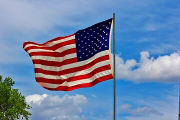 american flag waving in the wind in Hutchinson Kansas USA with a blue sky and white clouds.