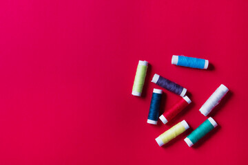 palette of spool of threads on red paper background, with copy space