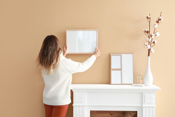 Woman hanging blank photo frame on wall