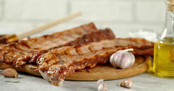 Raw ribs on a cutting board with garlic slowly rotate.