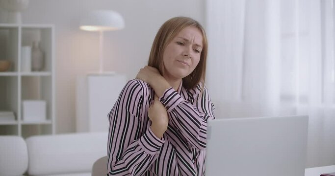 young woman working with laptop is feeling pain in neck, chronic cervical osteochondrosis, e-learning at home