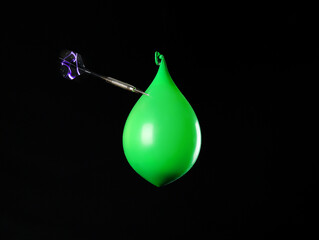 Throwing of dart in balloon with water on dark background