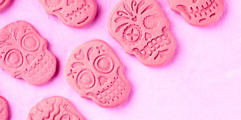 Halloween or the Day of the Dead panorama, a greeting card or invitation design template with skull ginger cookies pattern, shot from the top on a pink background with a place for text