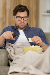 smiling man sitting on the sofa watching tv