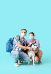 Young couple with medical masks and cute Husky dog on color background. Concept of epidemic