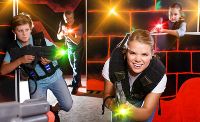 Group of happy kids and adults with laser guns playing on lasertag arena