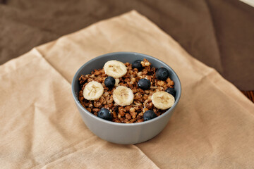 Close up of homemade granola in a plate with nuts, honey, blueberries, banana and other natural ingredients served on napkin