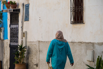 Fototapeta na wymiar Casablanca, Morocco: 09/07/2019 : Portrait of a muslim woman with her head covered walking in the city center of Casablanca in a sunny day. Woman crossing the streets of the eastern markets