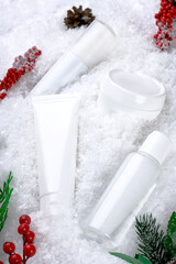 Cosmetics concept with Christmas decor on a snow. Winter moisturizing care for sensitive skin. A set of micellar water, face and body cream, cleansing skin lotion, skincare. Personal hygiene products