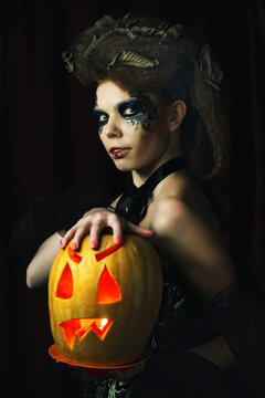 Halloween witch with carved pumpkin over red background.