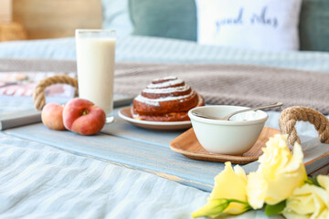 Tray with tasty breakfast on bed