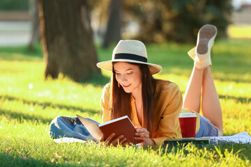Beautiful young woman reading book in park