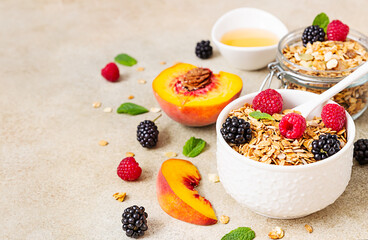 Homemade granola or muesli on stone background. Ingredients for healthy breakfast - granola, berries, peach, mint and honey.