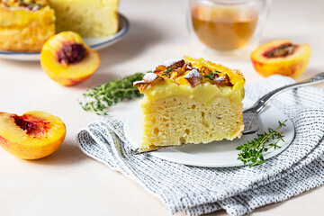 Delicious chiffon cake with custard cream and nectarines with herbal tea and thyme on light concrete background.