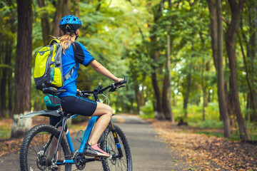 Caucasian woman cyclist rides mountain bike forest trails. leisure. Back view