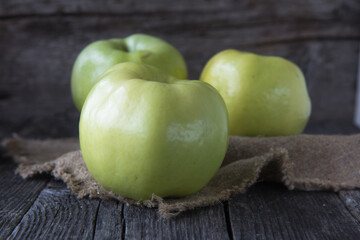 Green organic apple on rustic background.