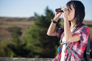 woman looking through binoculars in the countryside