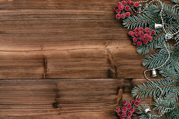 Christmas frame made of blue fir tree branches, red viburnum berries and holiday decorations on the dark wooden rustic background.Christmas background.Copy space for text, top view, flat lay