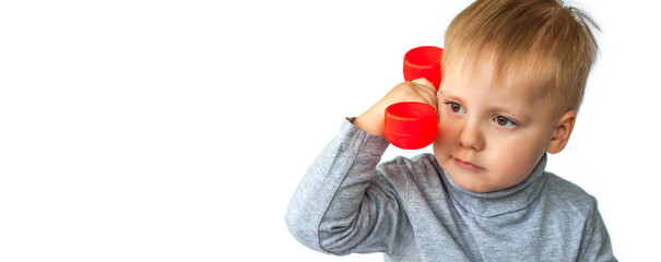 Portrait of a surprised cute little boy holding a red telephone receiver. The child is isolated on a white background. The concept of an advertising banner.