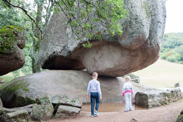 Bulgaria. Thracian sanctuary Beglik Tash. Children by a stone block weighing 200 tons, which rests on two points of support.