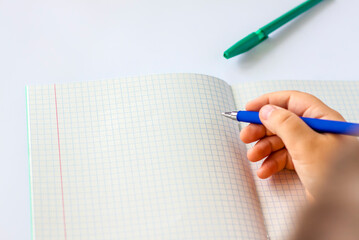 The child holds his hands over an open notebook and is going to write in it. Close-up of a child's hands.