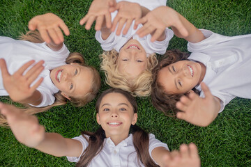 Children in white lying on the grass and stretching hands