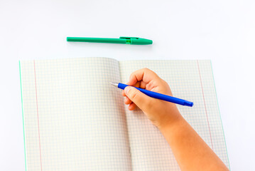 The child holds his hands over an open notebook and is going to write in it. Close-up of a child's hands.