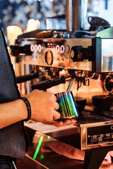 Close-up of barista hands whipping milk for coffee espresso, making cappuccino or latte. A professional barista preparing coffee with inspiration on the bar counter